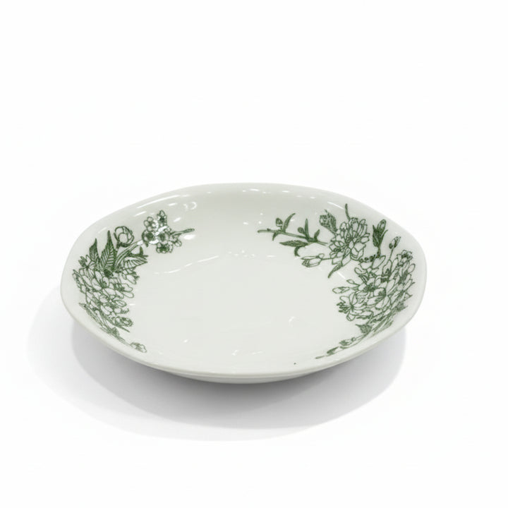 White ceramic bowl with green floral patterns on a white background