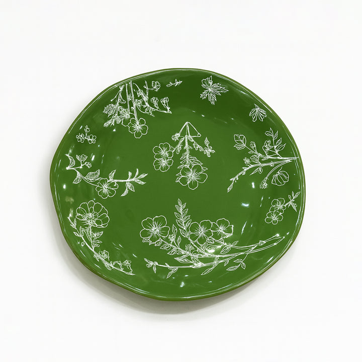 Green plate with white floral patterns on a white background