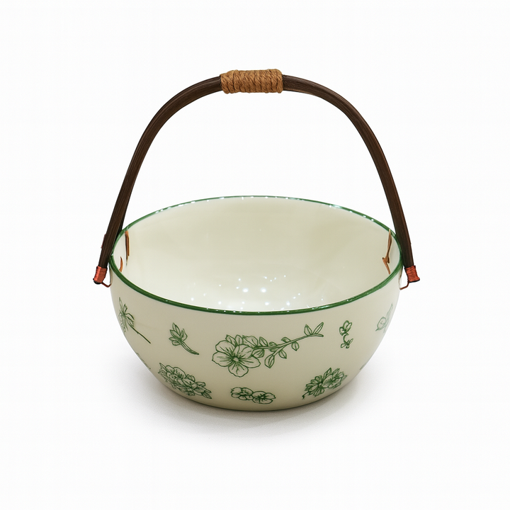 White ceramic bowl with green floral patterns and a brown handle on a white background