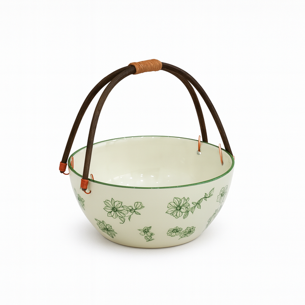 White ceramic bowl with green floral patterns and a brown handle on a white background