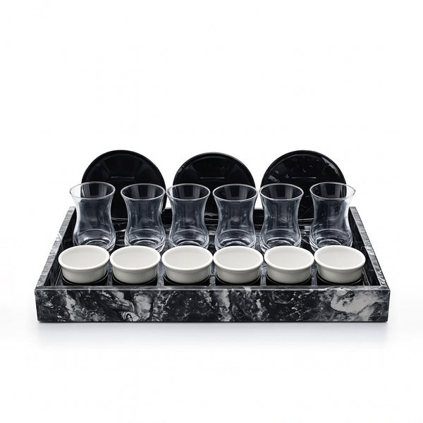 Set of glass tumblers and small bowls on a marble tray with black rim.
