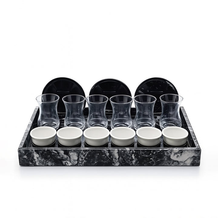 Set of glass tumblers and small bowls on a marble tray with black rim.
