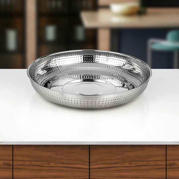 Silver hammered metal bowl on a white surface with a blurred background