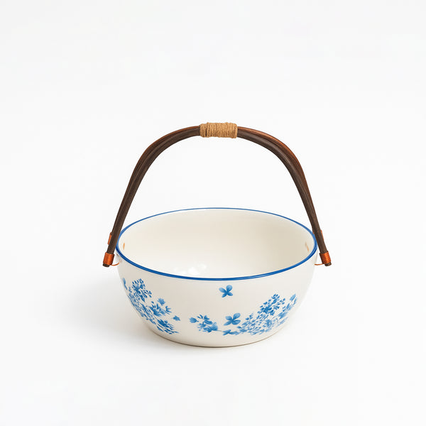 Ceramic bowl with blue floral pattern and brown handle on a white background