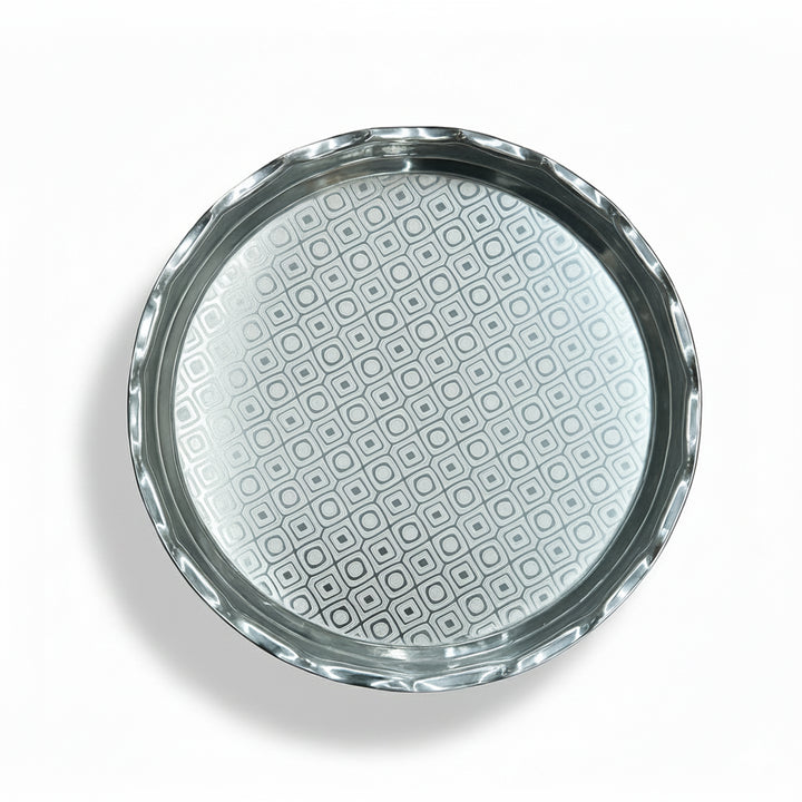 Round glass object with silver rim and geometric pattern on a white background