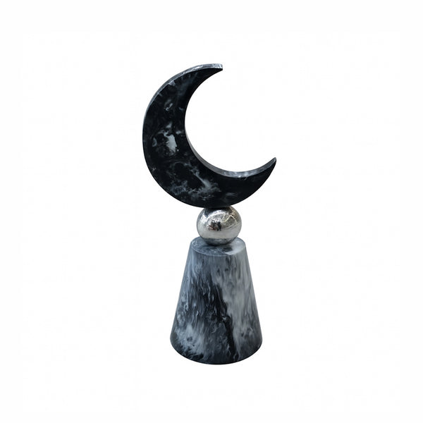 Decorative object with a black crescent moon on a gray cylindrical base against a white background