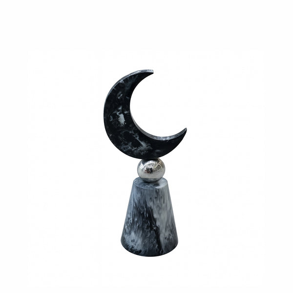 Decorative item with a black crescent moon and silver sphere on a white background