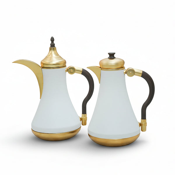 Two white ceramic teapots with gold and black accents on a white background
