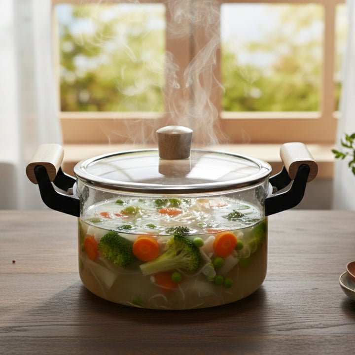 Steaming pot of soup with vegetables on a wooden table