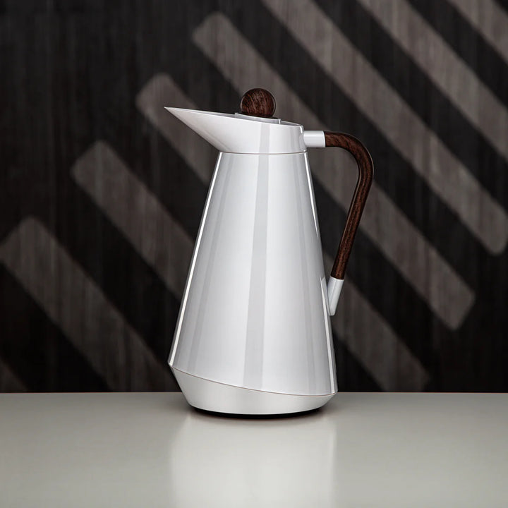 Silver coffee pot with wooden handle on a reflective surface and dark background