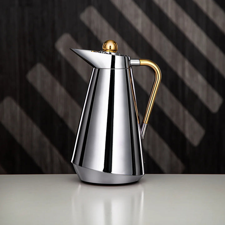 Stainless steel coffee pot with gold accents on a dark background