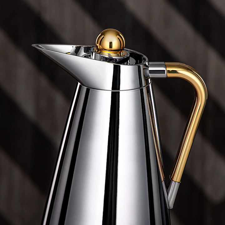 Stainless steel and gold coffee pot on a dark background
