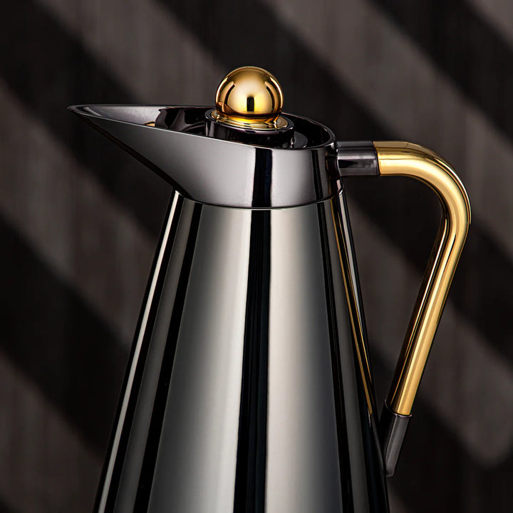 Stainless steel and gold coffee pot on a dark background