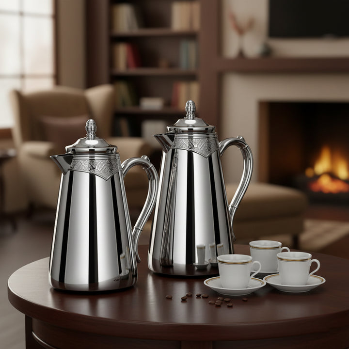 Stainless steel coffee pots and cups on a wooden table with a cozy living room background.