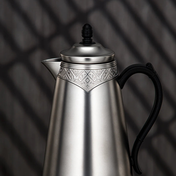 Silver teapot with black handle on a dark background