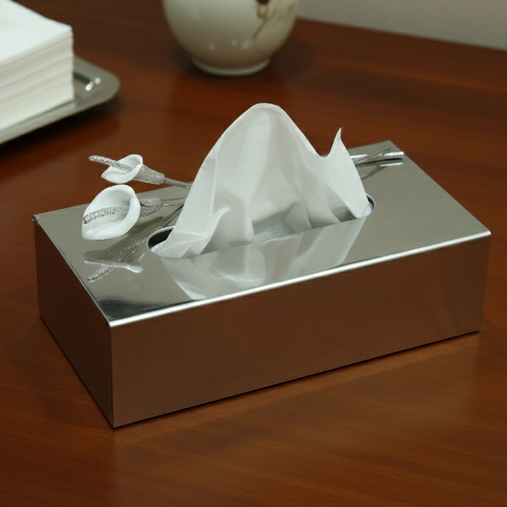 Silver tissue box with white tissues on a wooden surface