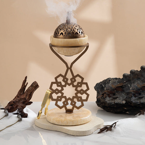 Decorative incense burner with smoke on a marble surface with natural elements.