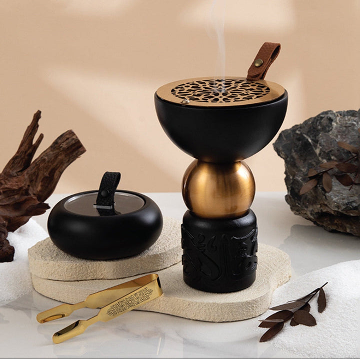 Decorative incense burner with smoke, rocks, and leaves on a neutral background