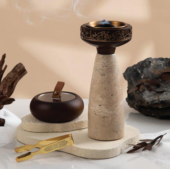 Decorative stone incense burner with a small pot and tools on a neutral background