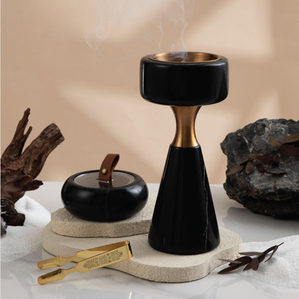 Black and gold incense burner with smoke, surrounded by decorative elements on a neutral background