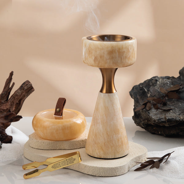 Decorative stone candle holder with a small stone apple and tool on a neutral background