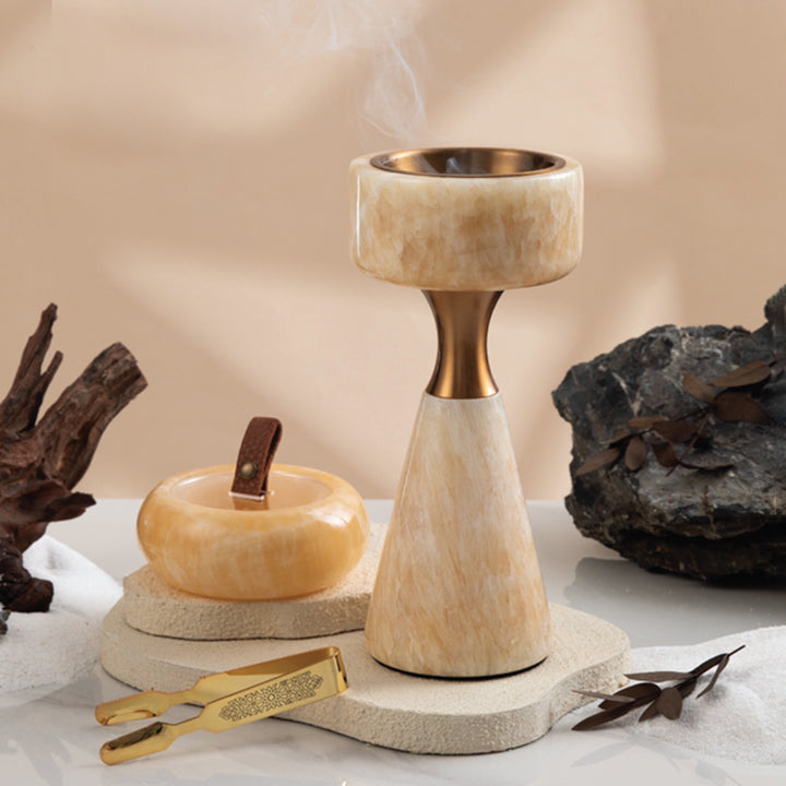 Decorative stone candle holder with a small stone apple and tool on a neutral background