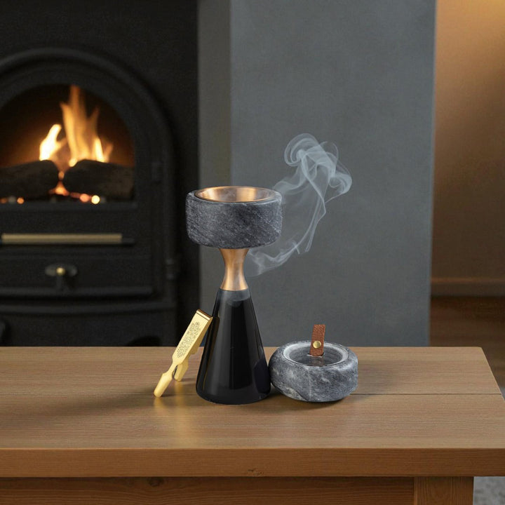 Incense burner with smoke on a wooden surface in front of a fireplace.